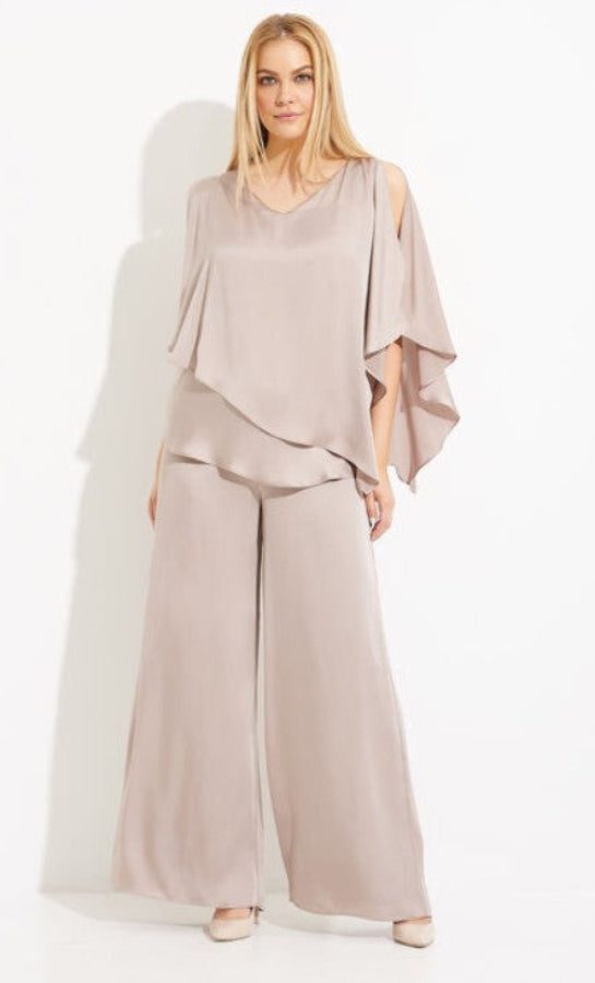Woman wearing a beige outfit with a flowing top and wide-leg pants on a white background
