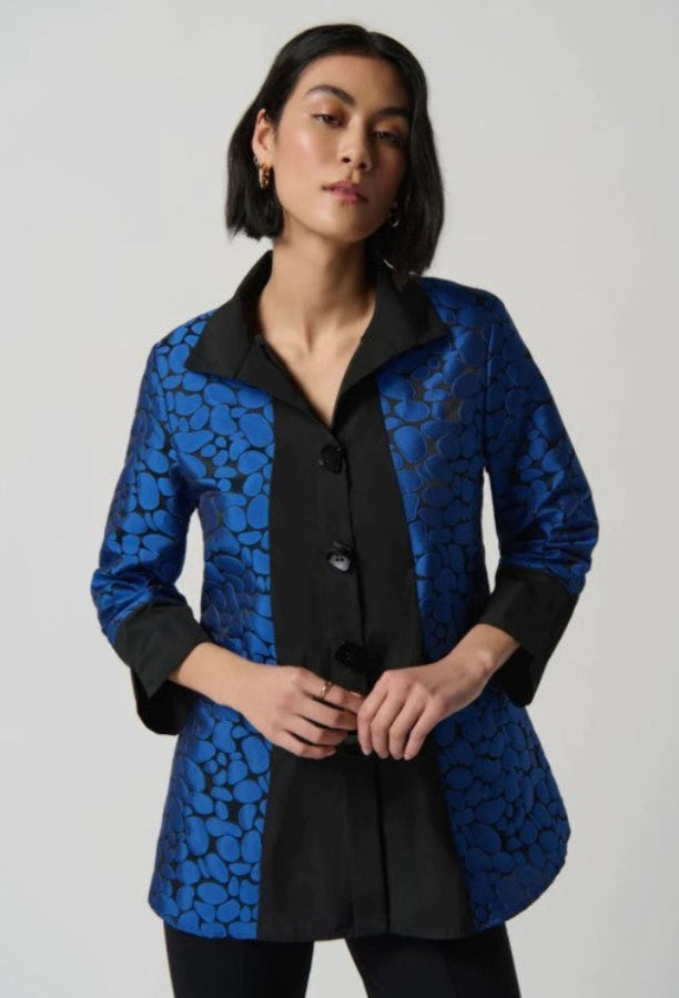Woman wearing a blue and black patterned coat against a plain background