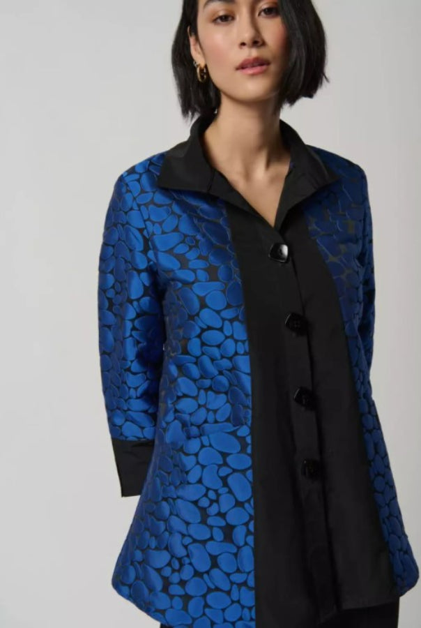 Woman wearing a blue and black patterned coat on a plain background