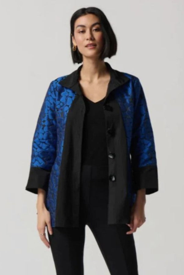 Woman wearing a black and blue patterned jacket on a plain background