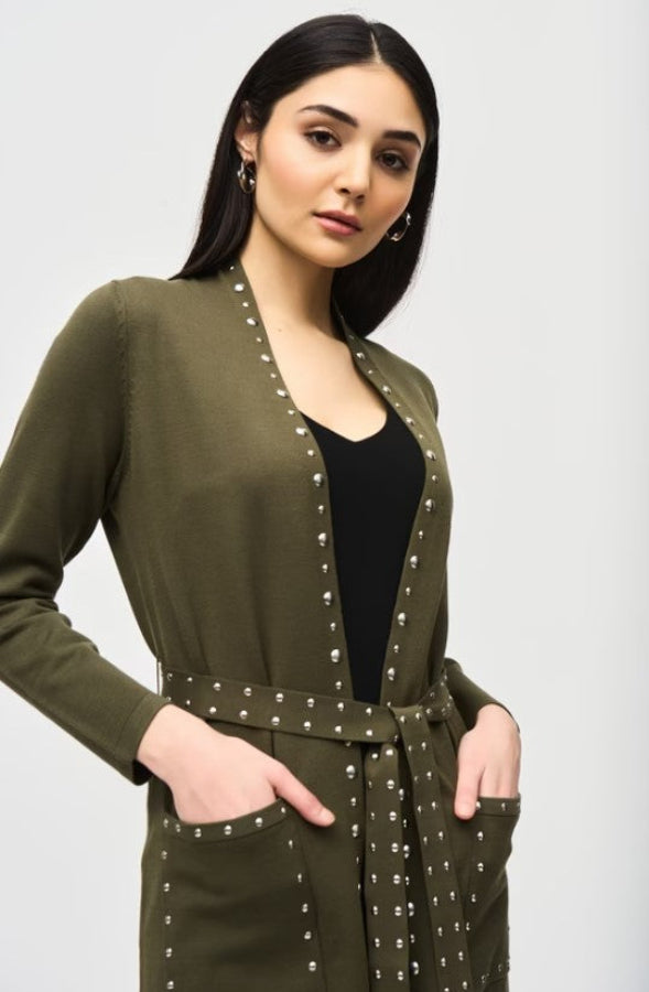 Woman wearing an olive green cardigan with pearl embellishments on a white background