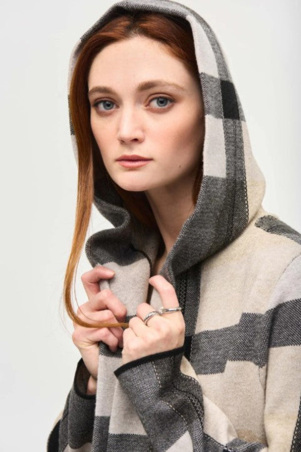 Person wearing a checkered hooded garment against a plain background