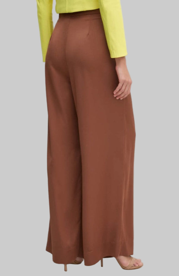 Brown wide-leg pants worn with a yellow top on a plain background