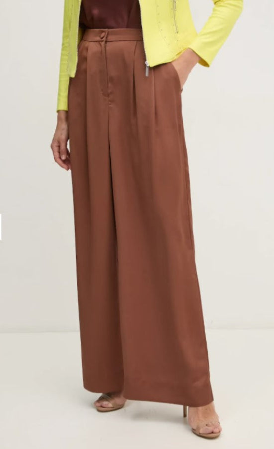 Brown wide-leg pants worn with a yellow top on a white background