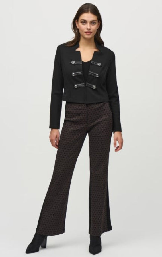 Woman wearing a black jacket and patterned pants on a white background