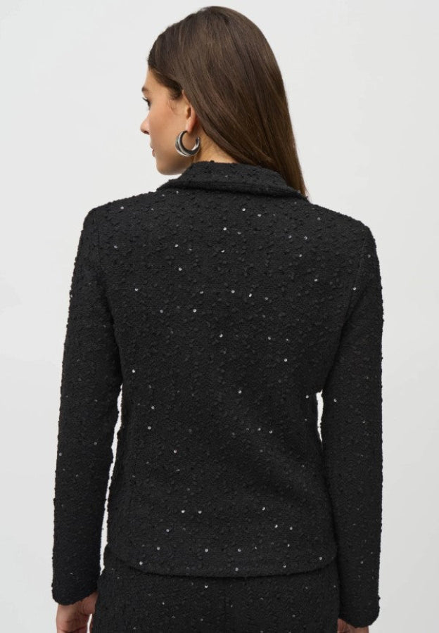Woman wearing a black textured jacket on a light gray background