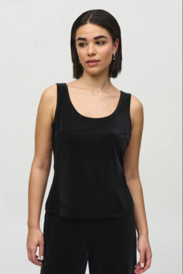 Woman wearing a black tank top against a plain background