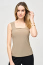 Woman wearing a beige sleeveless top against a plain background