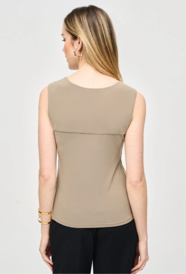 Woman wearing a beige sleeveless top on a plain background