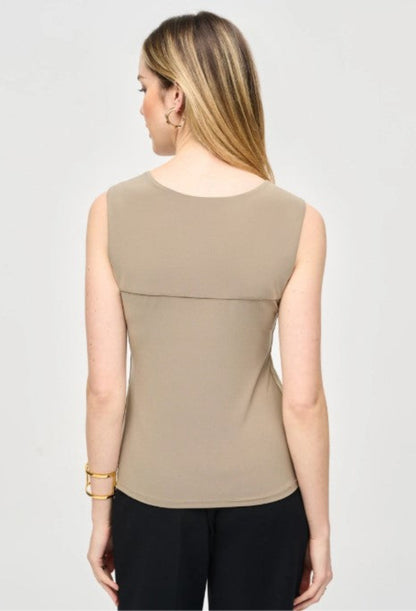 Woman wearing a beige sleeveless top on a plain background