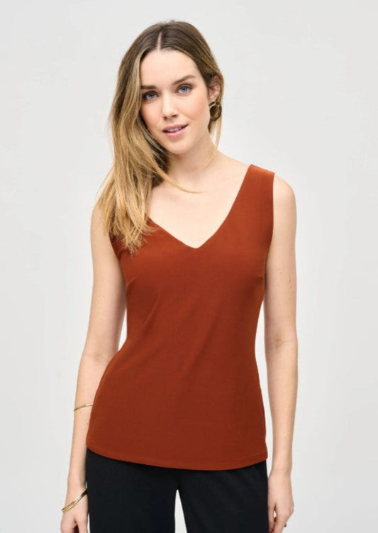 Woman wearing a rust-colored sleeveless top against a plain background