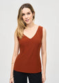 Woman wearing a rust-colored sleeveless top against a plain background