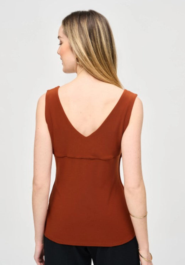 Woman wearing a rust-colored sleeveless top on a gray background