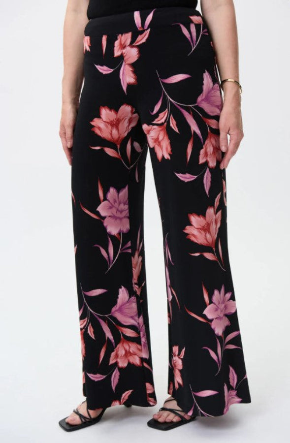 Black pants with pink floral pattern worn by a person on a white background