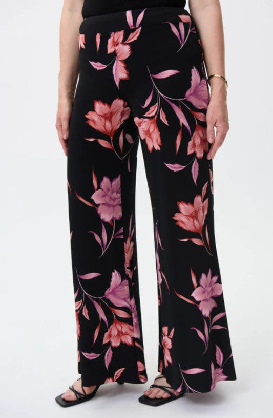 Black pants with pink floral pattern worn by a person on a white background