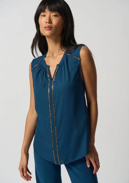 Woman wearing a blue sleeveless top with decorative trim on a white background