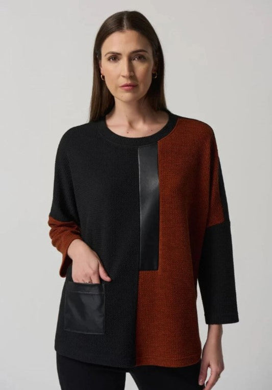 Woman wearing a black and brown color-blocked top on a plain background