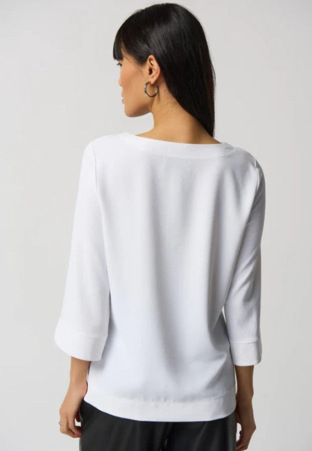 Woman wearing a white blouse with three-quarter sleeves on a plain background