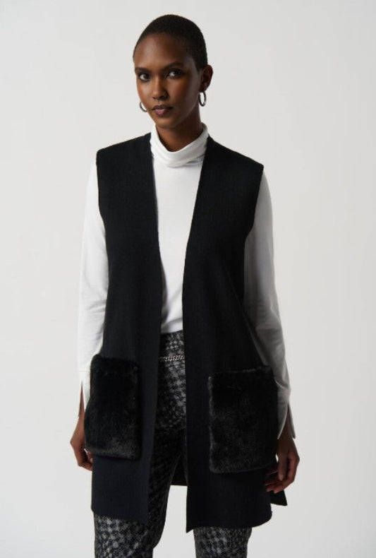 Person wearing a black vest over a white shirt on a plain background