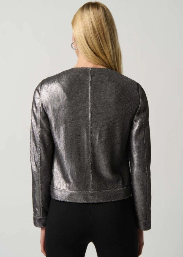 Person wearing a metallic silver jacket on a plain background