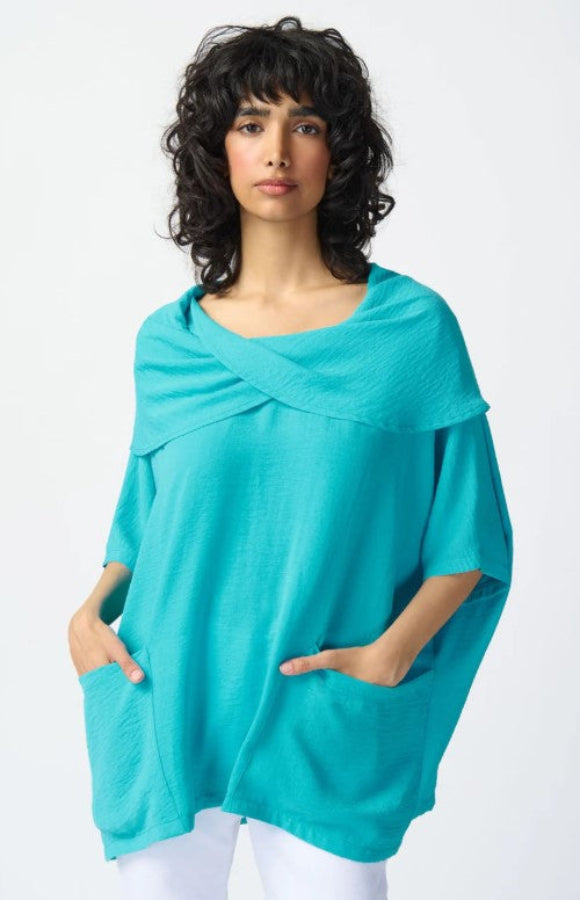 Woman wearing a turquoise poncho against a white background