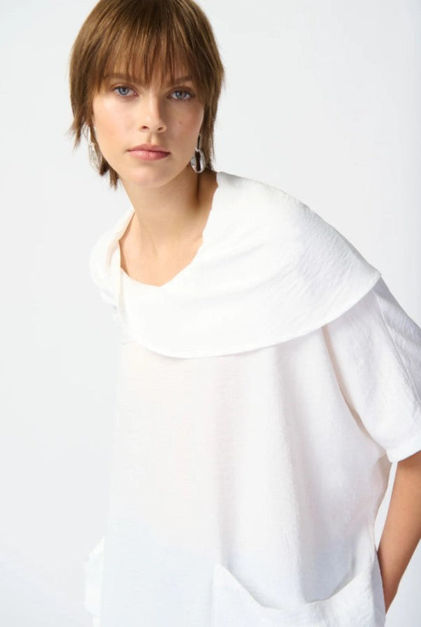 Woman wearing a white blouse with a large collar against a plain background
