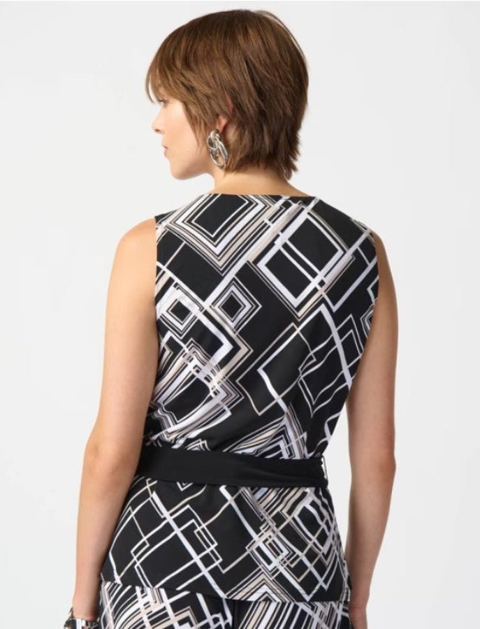 Woman wearing a black and white geometric patterned top on a plain background