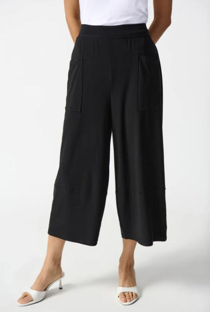 Person wearing black wide-leg pants on a white background