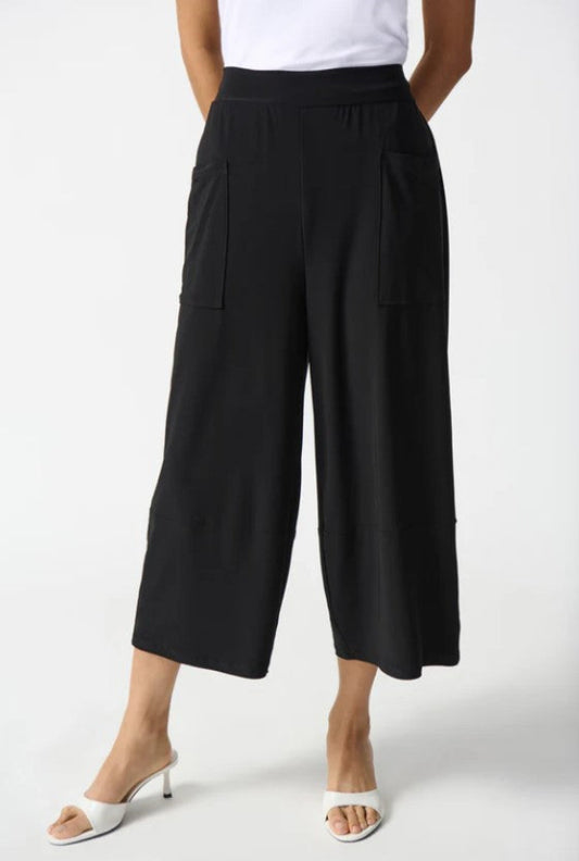 Person wearing black wide-leg pants on a white background