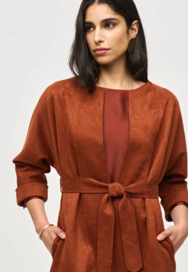 Woman wearing a brown suede coat against a plain background