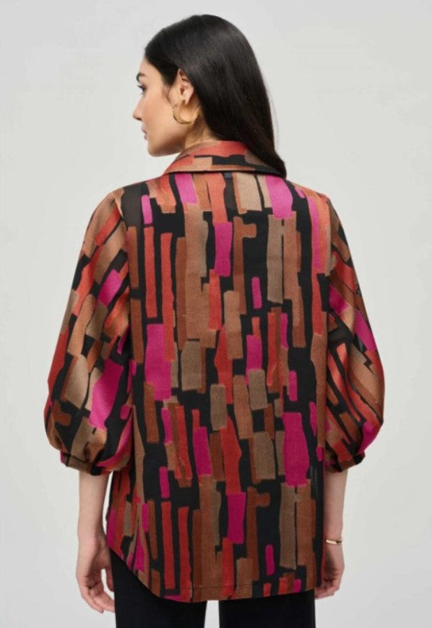 Woman wearing a colorful patterned jacket against a plain background