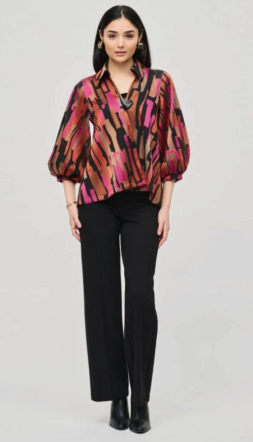 Woman wearing a colorful patterned jacket and black pants on a gray background