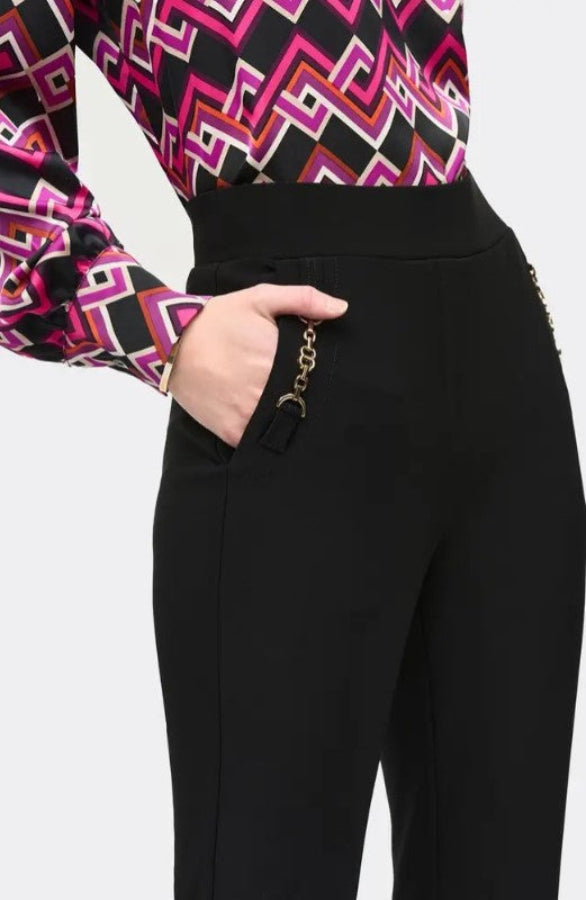 Black pants with a gold chain detail worn by a person, on a white background