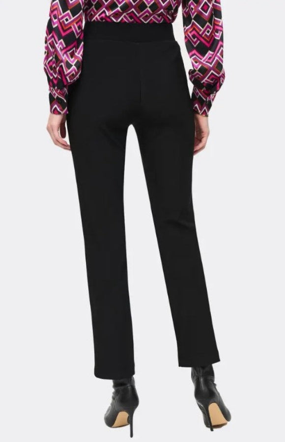 Black pants worn with a patterned top on a white background