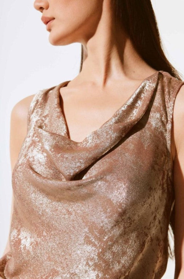 Close-up of a person wearing a sparkly bronze sleeveless top against a white background