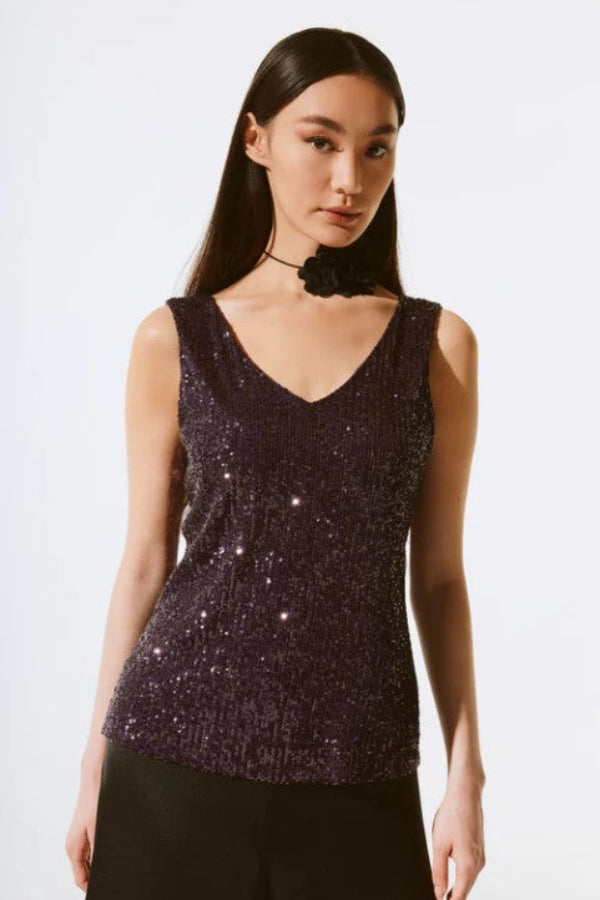 Woman wearing a sparkly purple top against a white background