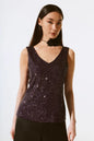 Woman wearing a sparkly purple top against a white background