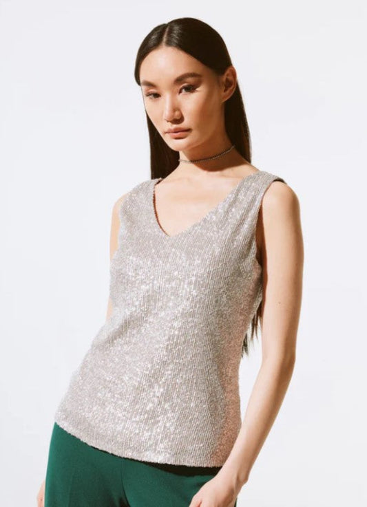 Woman wearing a silver sequin top against a white background