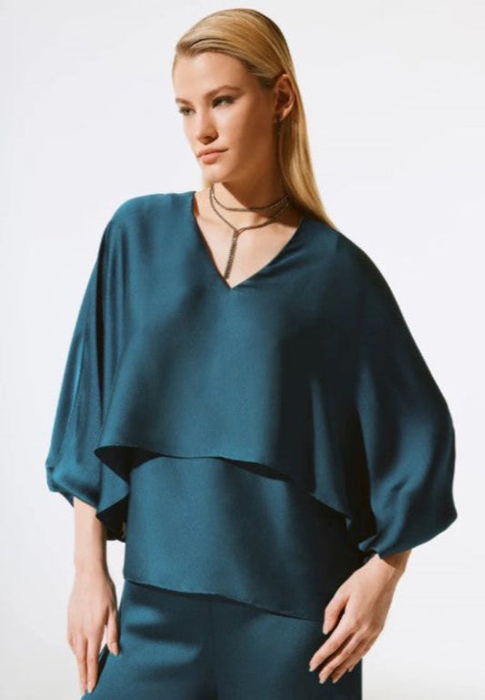 Woman wearing a teal blouse with a plain background