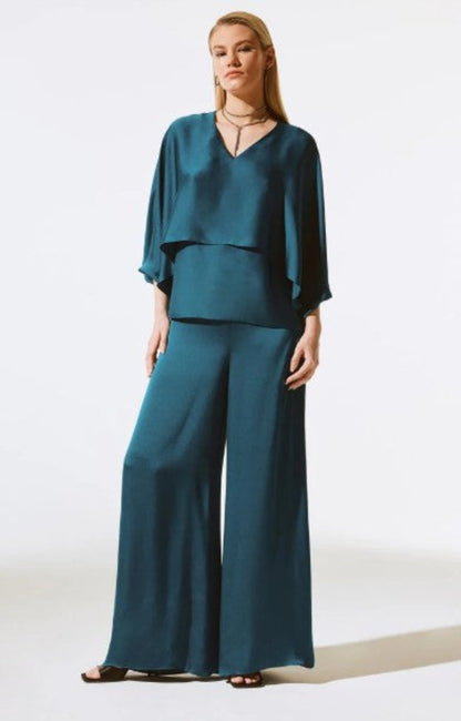 Woman wearing a teal outfit with a top and wide-leg pants on a white background