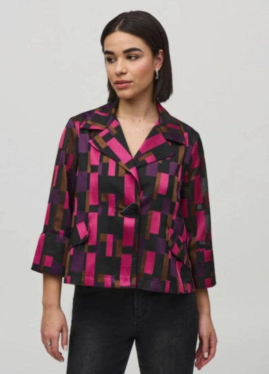Woman wearing a patterned jacket with geometric design on a plain background