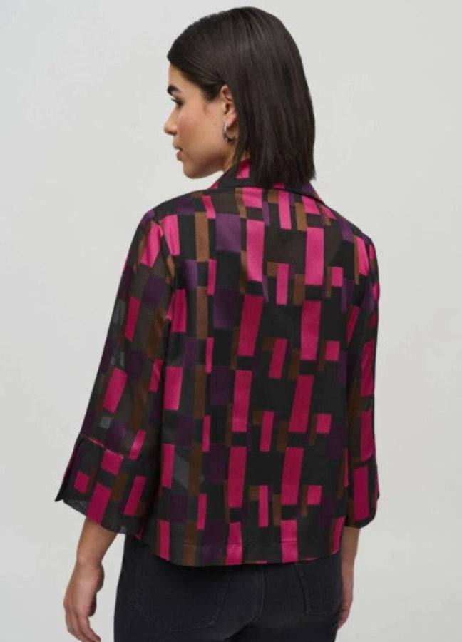Woman wearing a patterned jacket with geometric design on a plain background