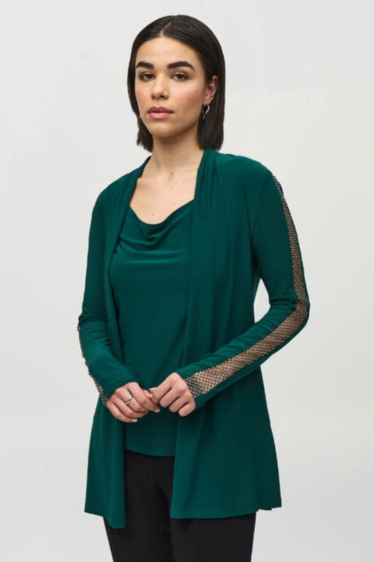 Woman wearing a green two-piece long-sleeve top with stud embellished mesh sleeves on a white background
