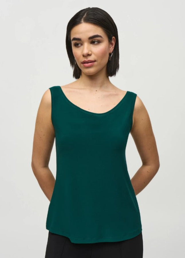 Woman wearing a green sleeveless top against a plain background