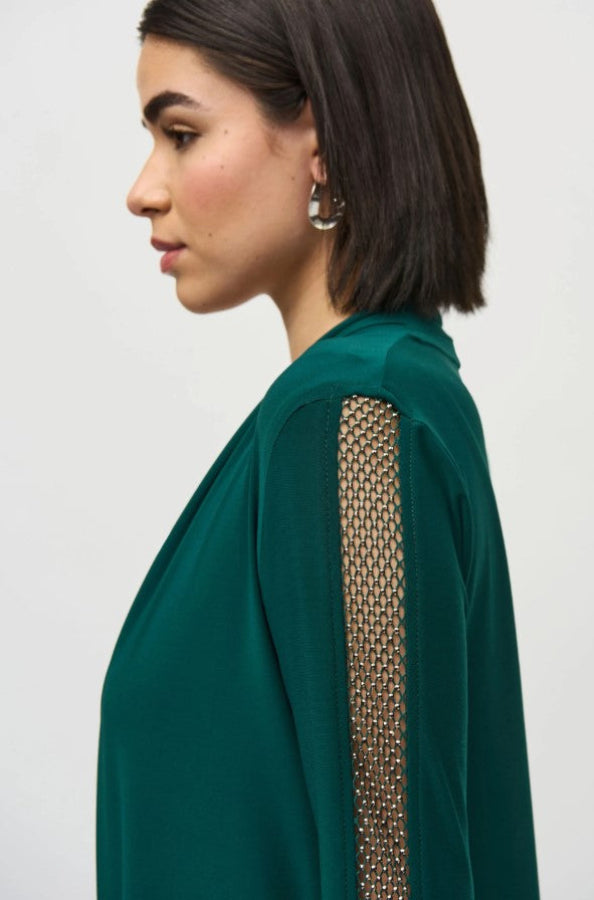 Close-up of a stud embellished mesh sleeve on a green top.