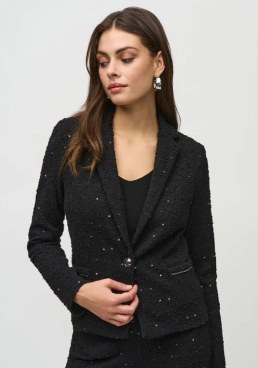 Woman wearing a black blazer with a textured pattern on a light gray background
