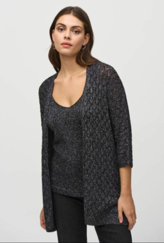 Woman wearing a dark patterned cardigan over a plain top on a light gray background