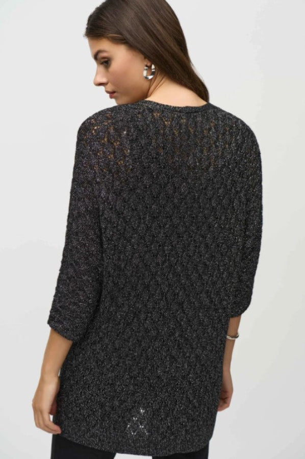 Woman wearing a black textured sweater against a white background