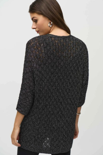 Woman wearing a black textured sweater against a white background
