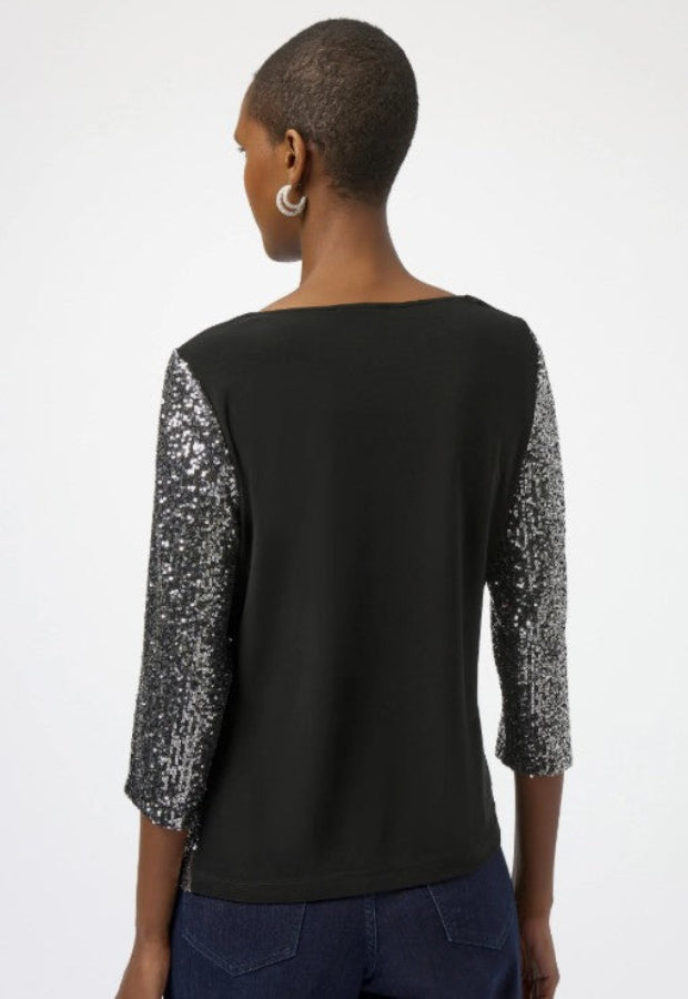 Black top with silver sequin sleeves worn by a model on a white background